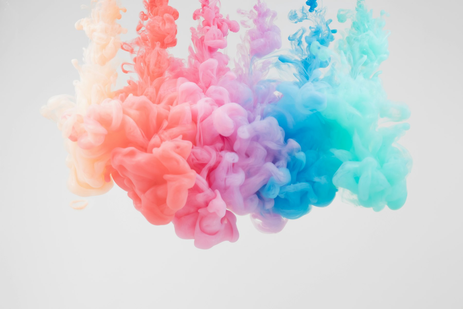 Clouds of pastel ink drifting and blending through clear water